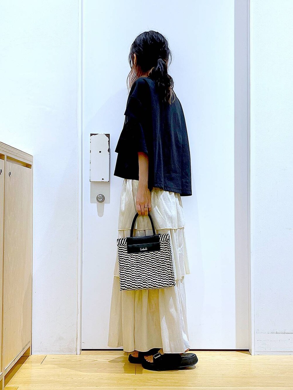 ブラック系のサンダル、ブラック系のショルダーバッグ、ゴールド系のスカートを着用したレディースの夏コーディネートの3枚目の写真