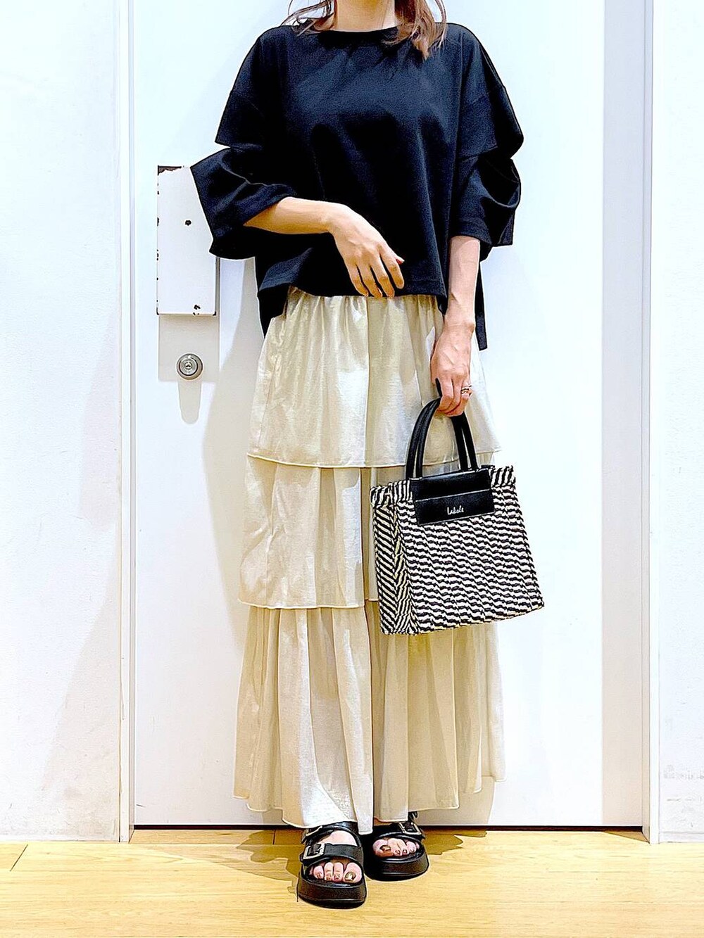 ブラック系のサンダル、ブラック系のショルダーバッグ、ゴールド系のスカートを着用したレディースの夏コーディネートの6枚目の写真