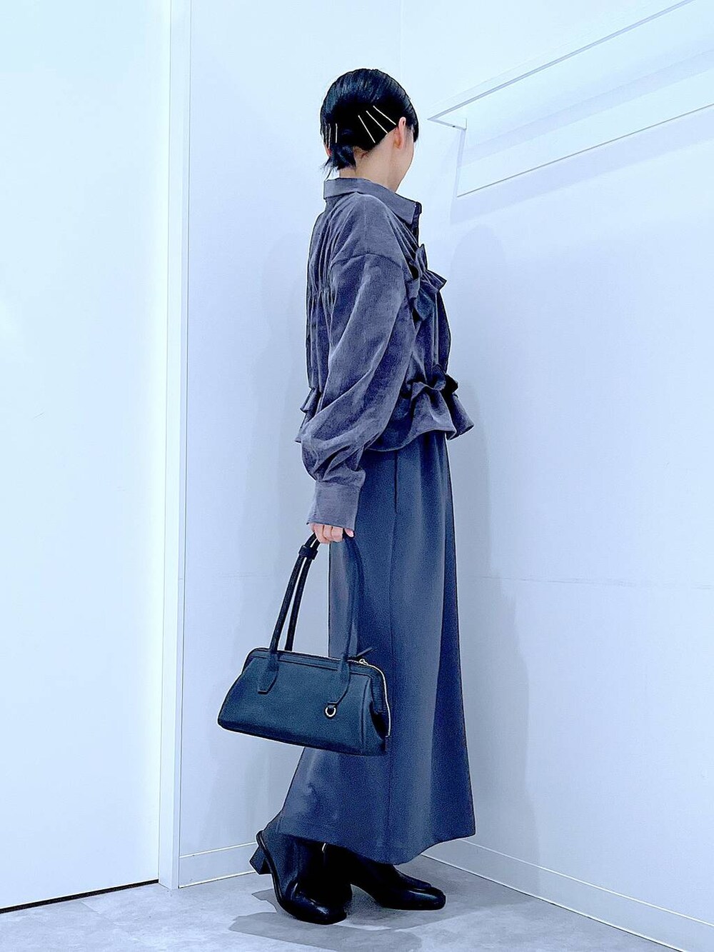 グレー系のスカート、ブラック系のブーツ、ブラック系のハンドバッグを着用したレディースの秋コーディネートの4枚目の写真