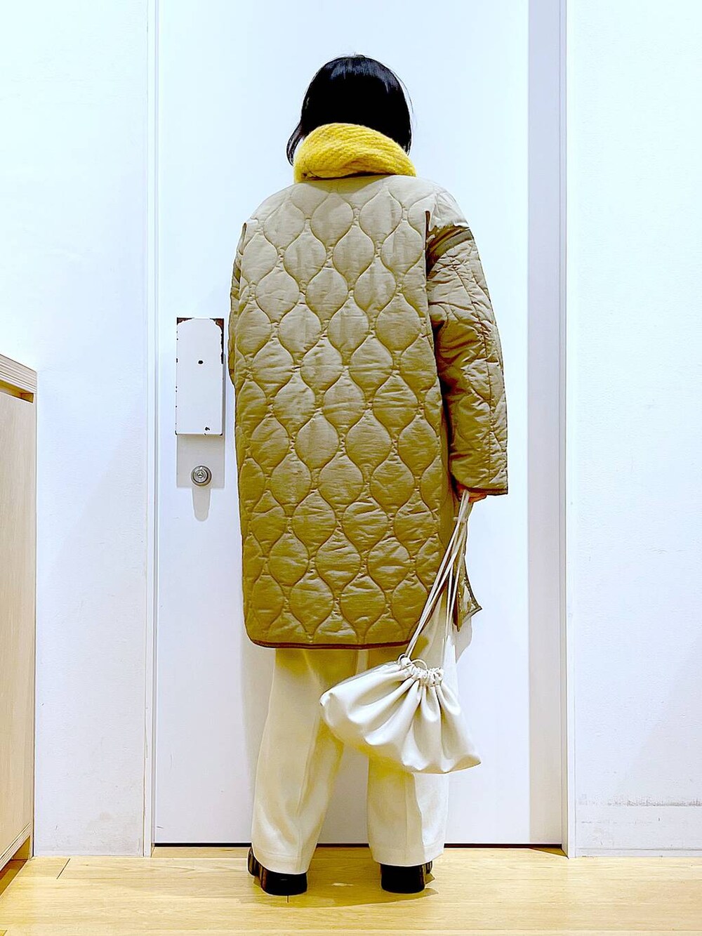 グリーン系のナイロンジャケット、ベージュ系のショルダーバッグ、ブラック系のブーツを着用したレディースの冬コーディネートの5枚目の写真