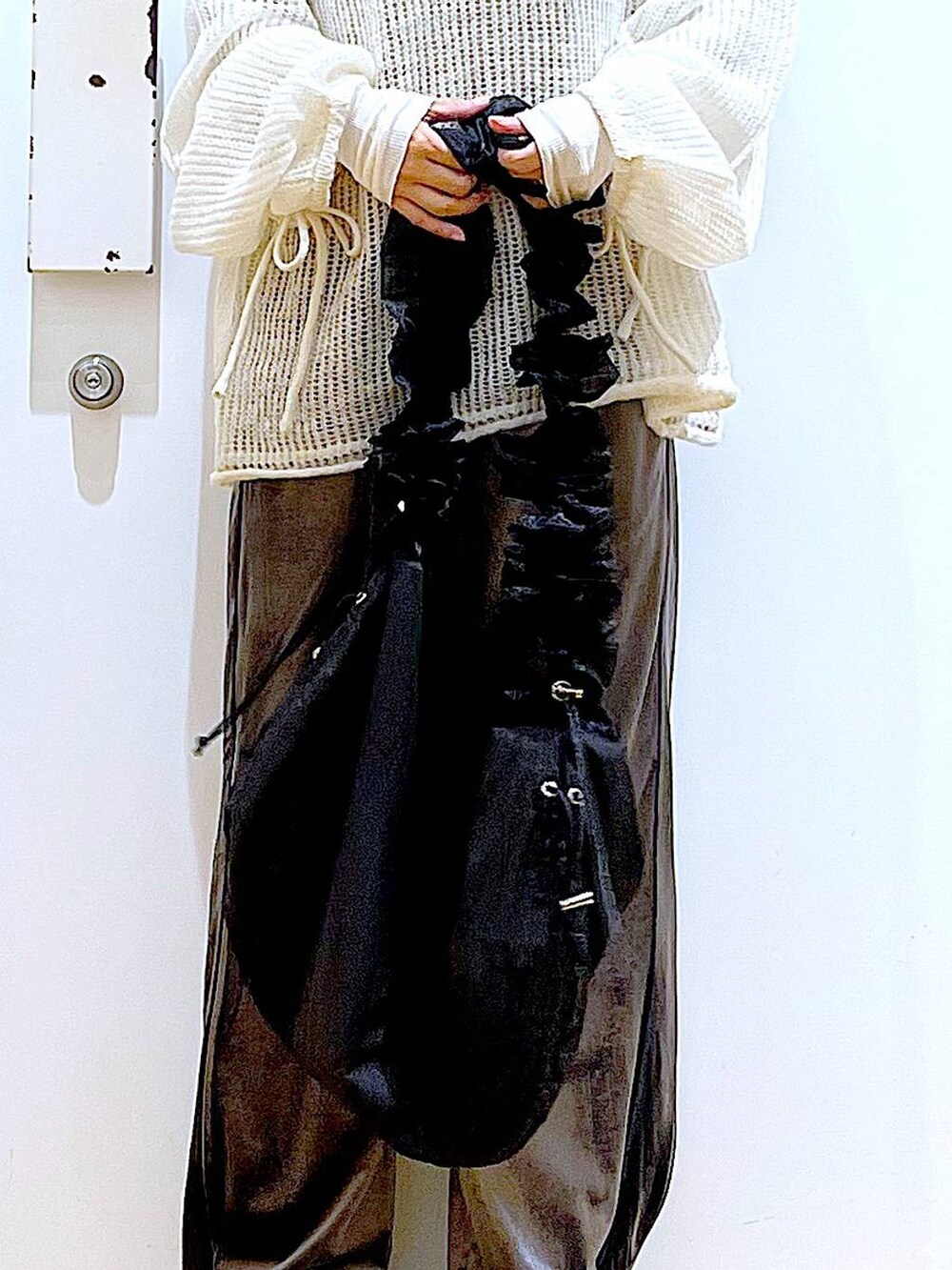 ブラック系のショルダーバッグ、ブラック系のブーツ、ホワイト系のニット/セーターを着用したレディースの冬コーディネートの9枚目の写真