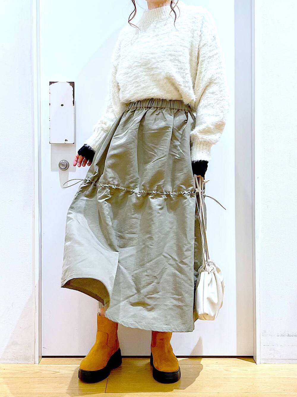 ベージュ系のショルダーバッグ、ベージュ系のブーツ、ベージュ系のニット/セーターを着用したレディースの冬コーディネートの6枚目の写真