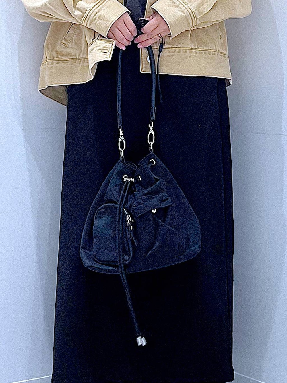 ブラック系のスカート、ベージュ系のデニムジャケット、ブラック系のショルダーバッグを着用したレディースの春コーディネートの9枚目の写真