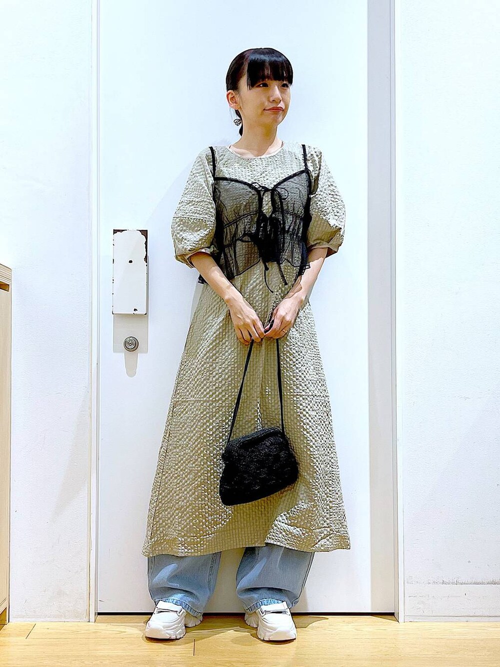 ホワイト系のスニーカー、ブルー系のデニムパンツ、ブラック系のショルダーバッグを着用したレディースの春コーディネートの2枚目の写真