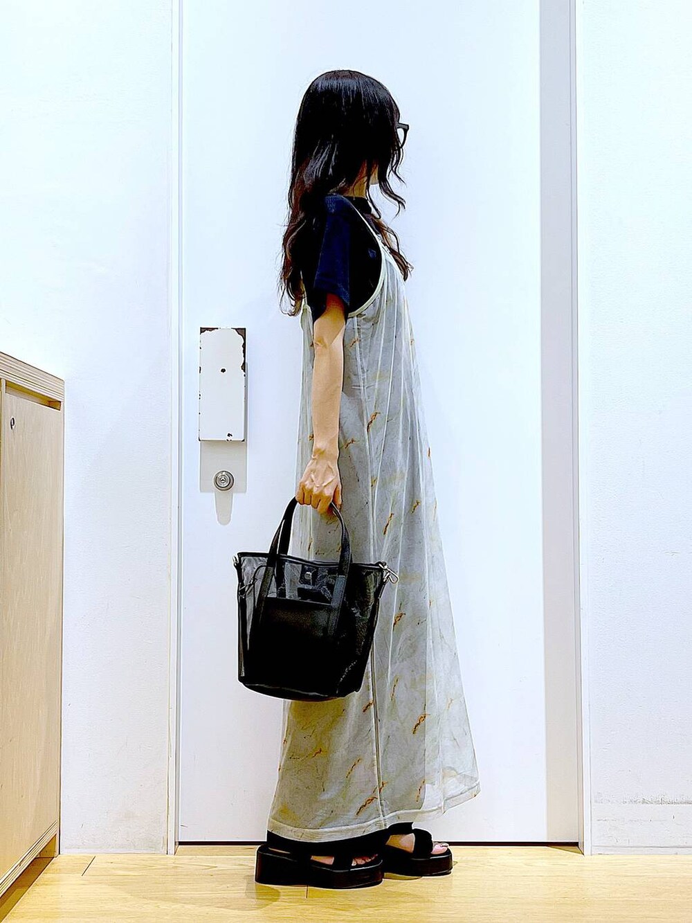 ブラック系のサンダル、ブラック系のトートバッグ、ベージュ系のワンピースを着用したレディースの夏コーディネートの4枚目の写真