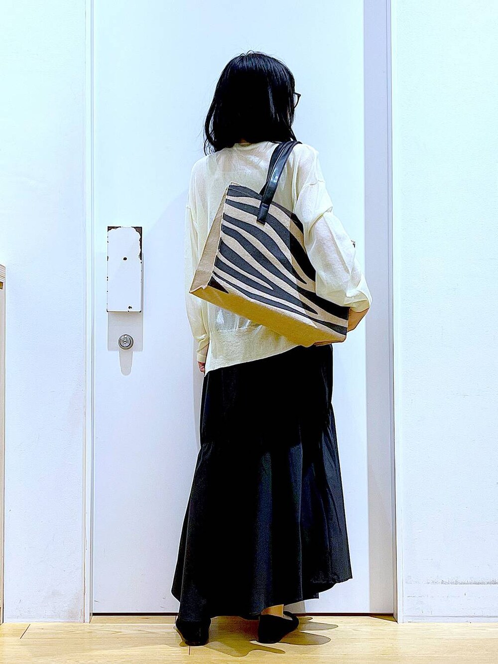 ホワイト系のニット/セーター、ブラック系のスカート、ブラック系のパンプスを着用したレディースの夏コーディネートの5枚目の写真