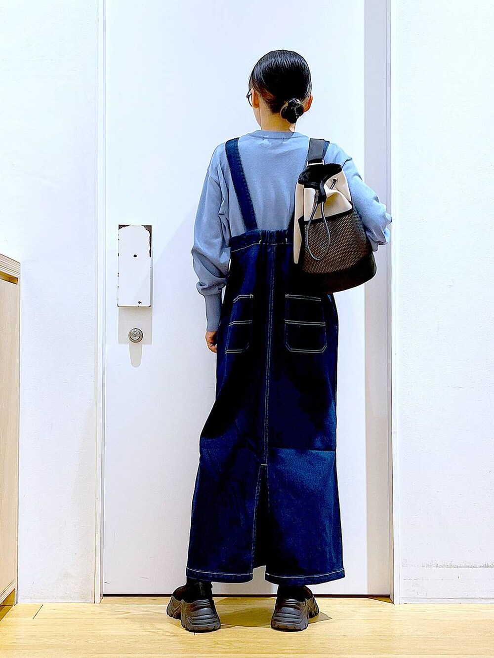 ブルー系のジャンパースカート、ブルー系のカーディガン/ボレロ、ブラック系のブーツを着用したレディースの春コーディネートの5枚目の写真