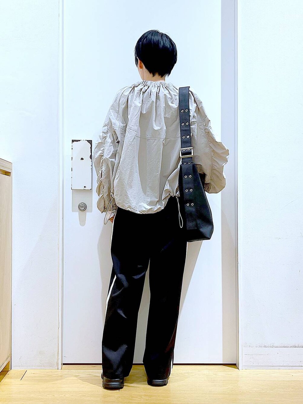 ブラック系のスラックス、ブラック系のスニーカー、ブラック系のショルダーバッグを着用したレディースの春コーディネートの5枚目の写真