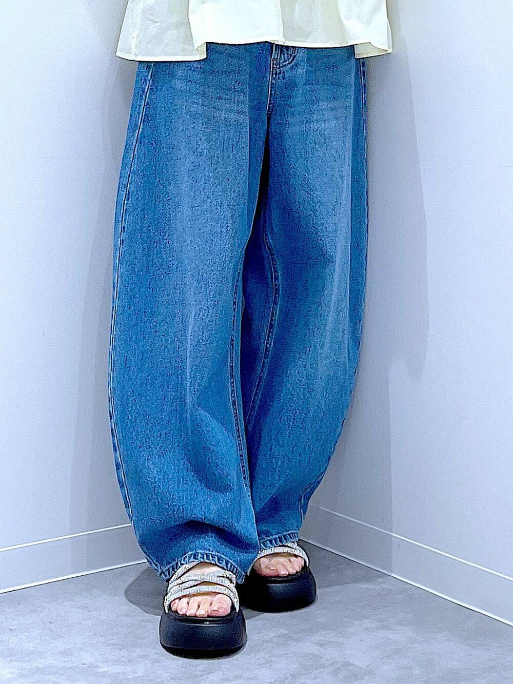 ブルー系のデニムパンツ、ベージュ系のショルダーバッグ、シルバー系のサンダルを着用したレディースの夏コーディネートの8枚目の写真