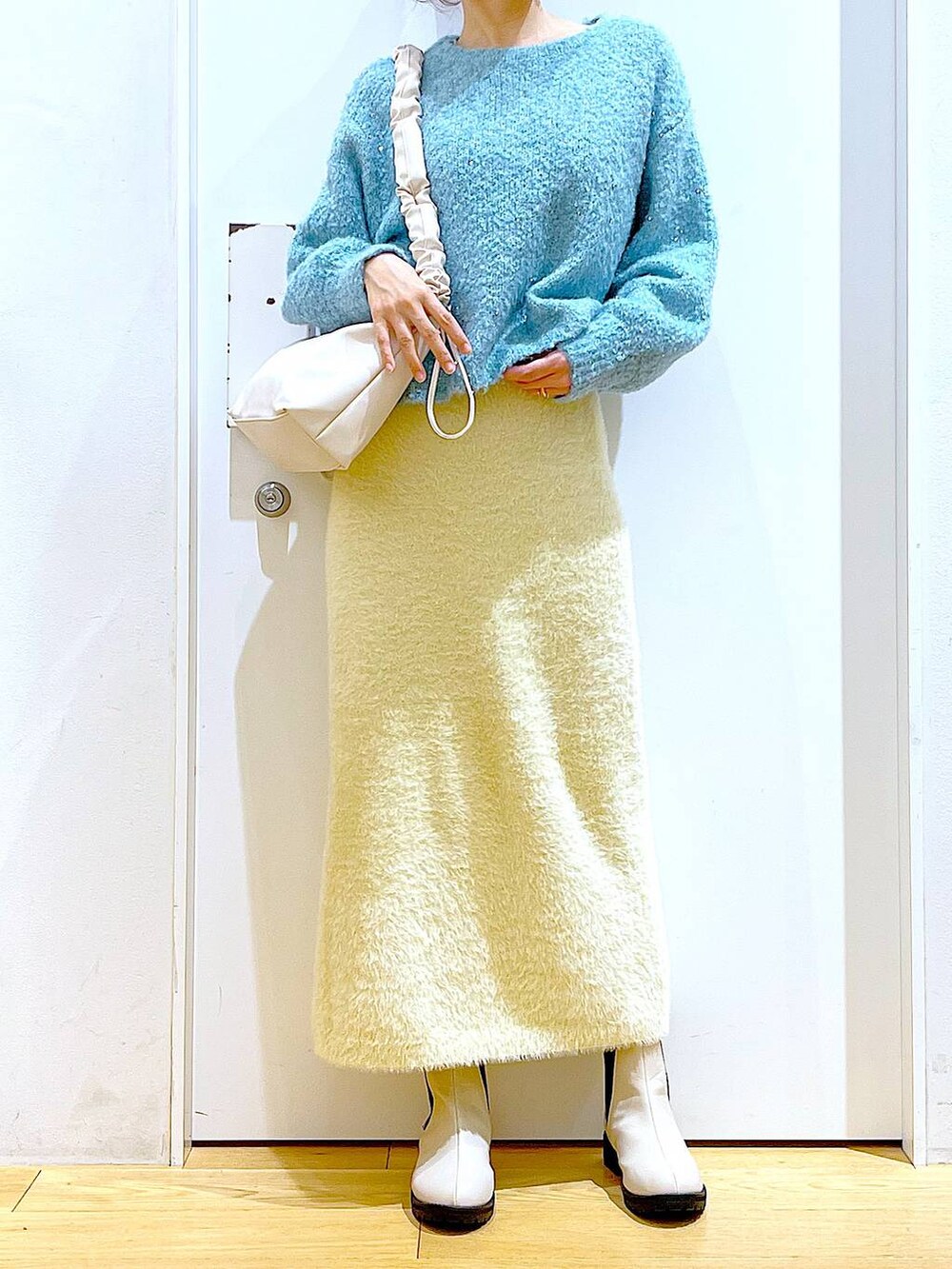 ホワイト系のショルダーバッグ、ベージュ系のブーツ、ホワイト系のスカートを着用したレディースの冬コーディネートの6枚目の写真