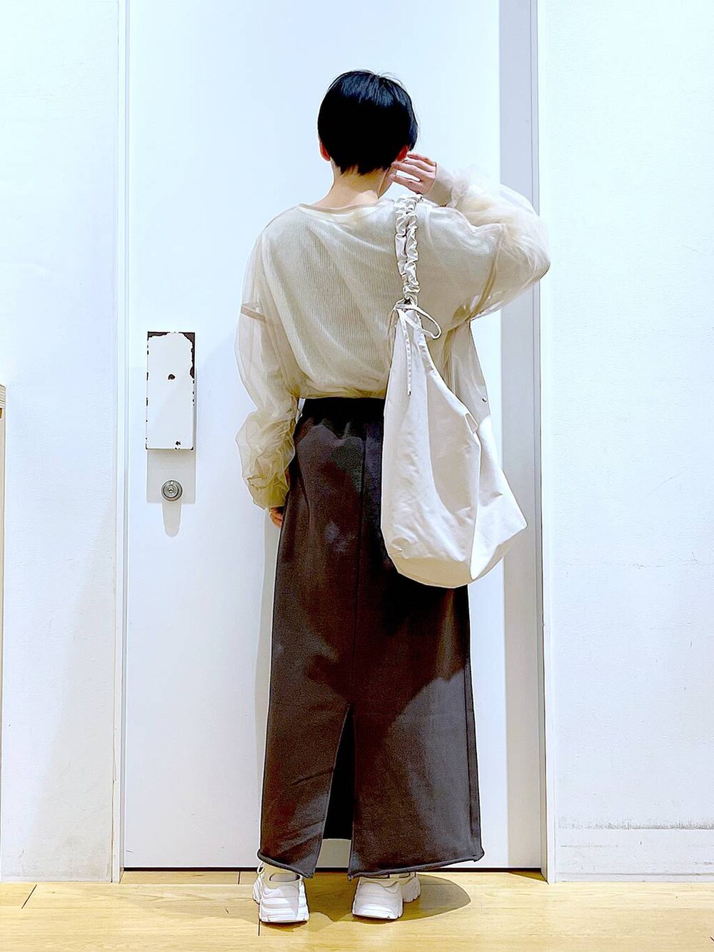 ホワイト系のショルダーバッグ、ホワイト系のスニーカー、グレー系のスカートを着用したレディースの春コーディネートの5枚目の写真