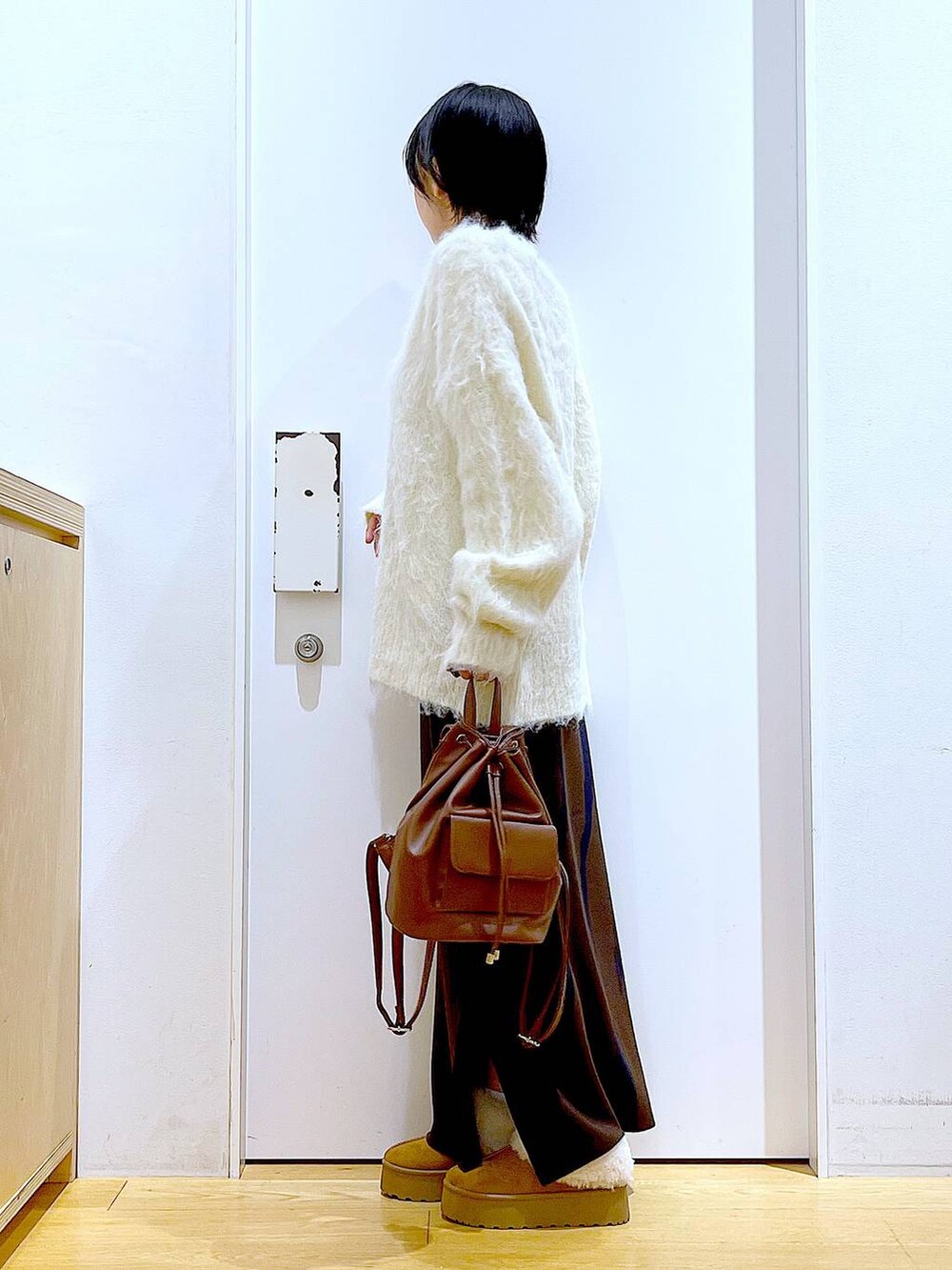 ベージュ系のニット/セーター、ブラウン系のバックパック/リュック、ブラウン系のスカートを着用したレディースの冬コーディネートの3枚目の写真