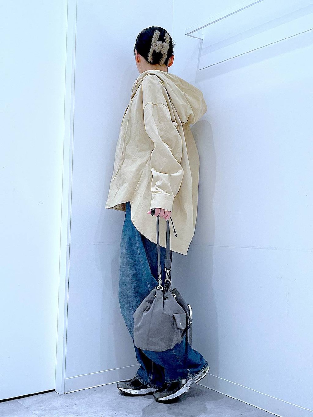 ブルー系のデニムパンツ、グレー系のショルダーバッグ、ベージュ系のその他トップスを着用したレディースの春コーディネートの3枚目の写真