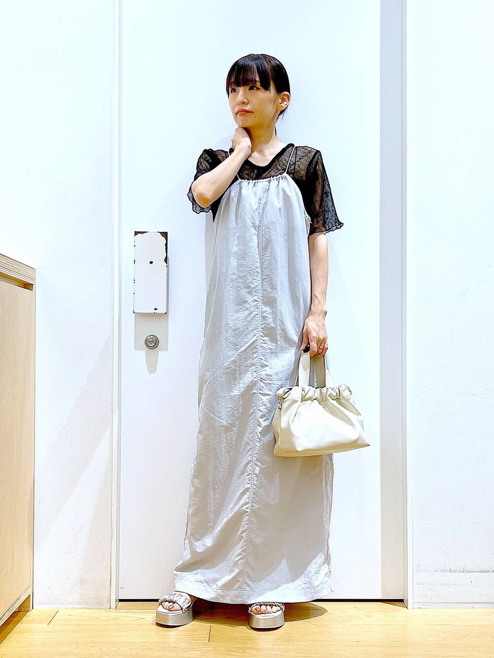 グレー系のワンピース、ホワイト系のショルダーバッグ、シルバー系のサンダルを着用したレディースの夏コーディネートの2枚目の写真