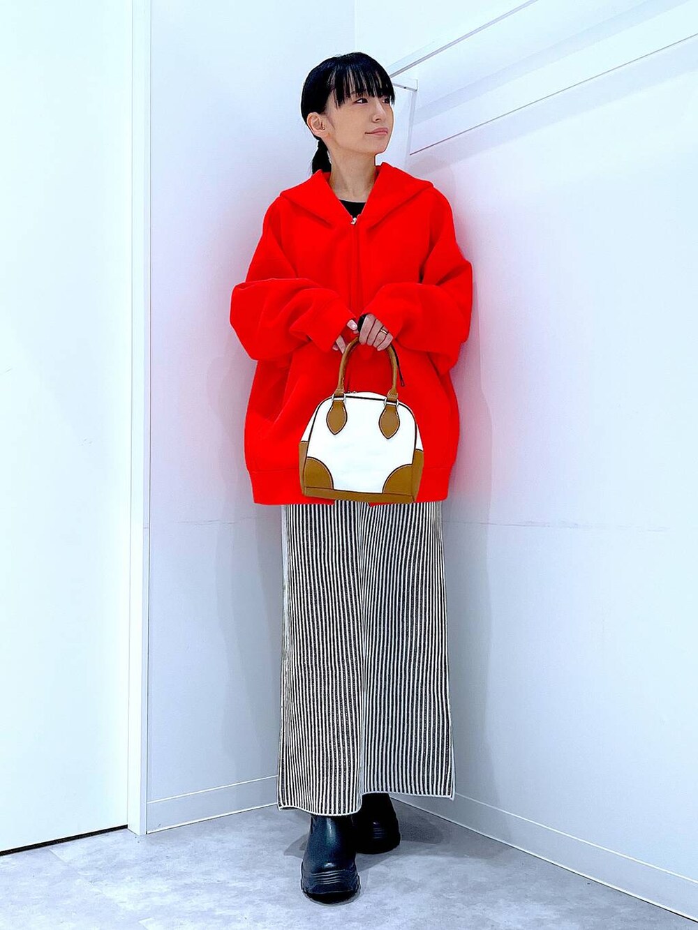 ブラック系のブーツ、ベージュ系のスカート、ホワイト系のハンドバッグを着用したレディースの秋コーディネートの2枚目の写真