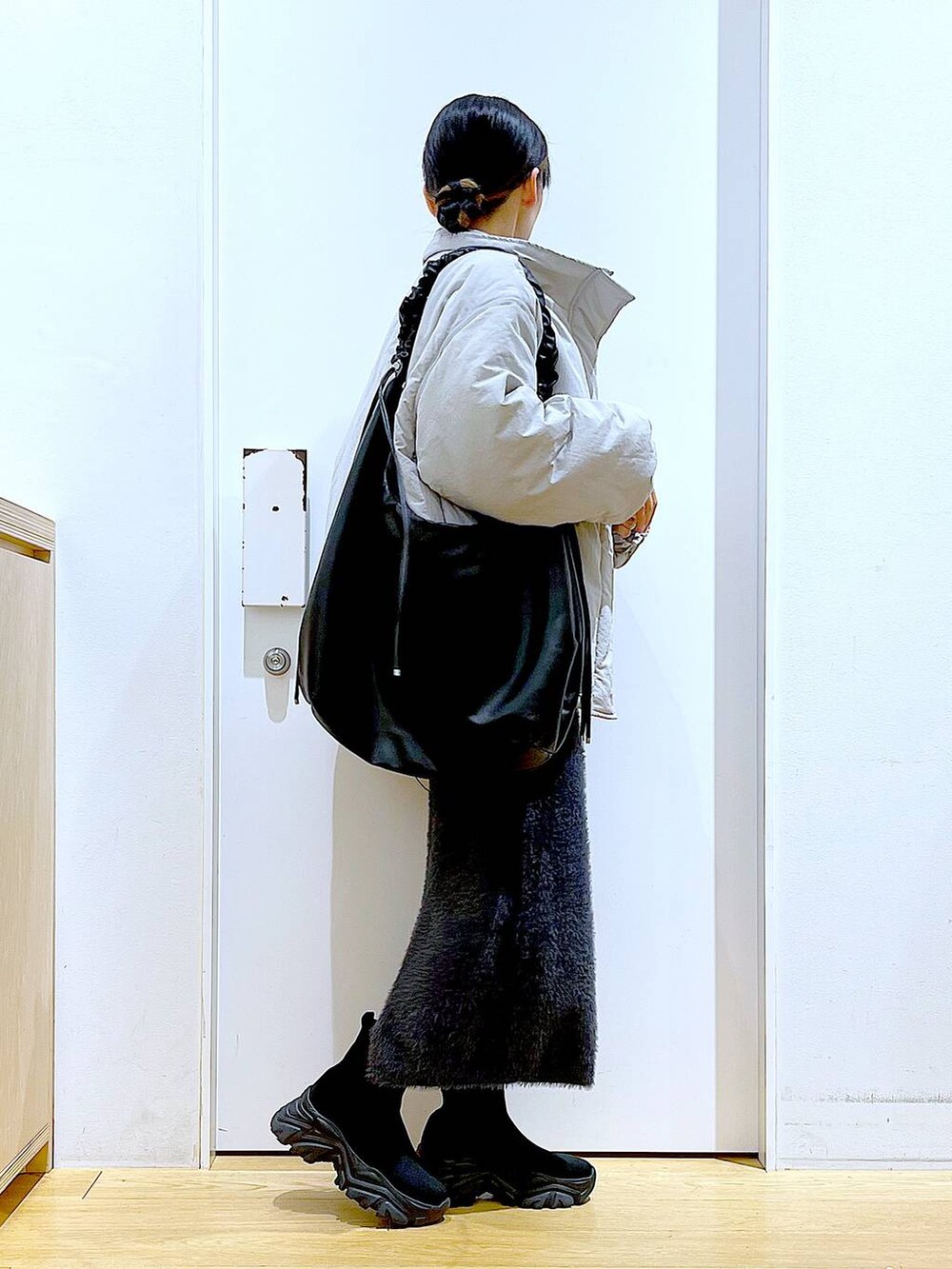 ブラック系のブーツ、ブルー系のスウェット、ブラック系のショルダーバッグを着用したレディースの冬コーディネートの4枚目の写真