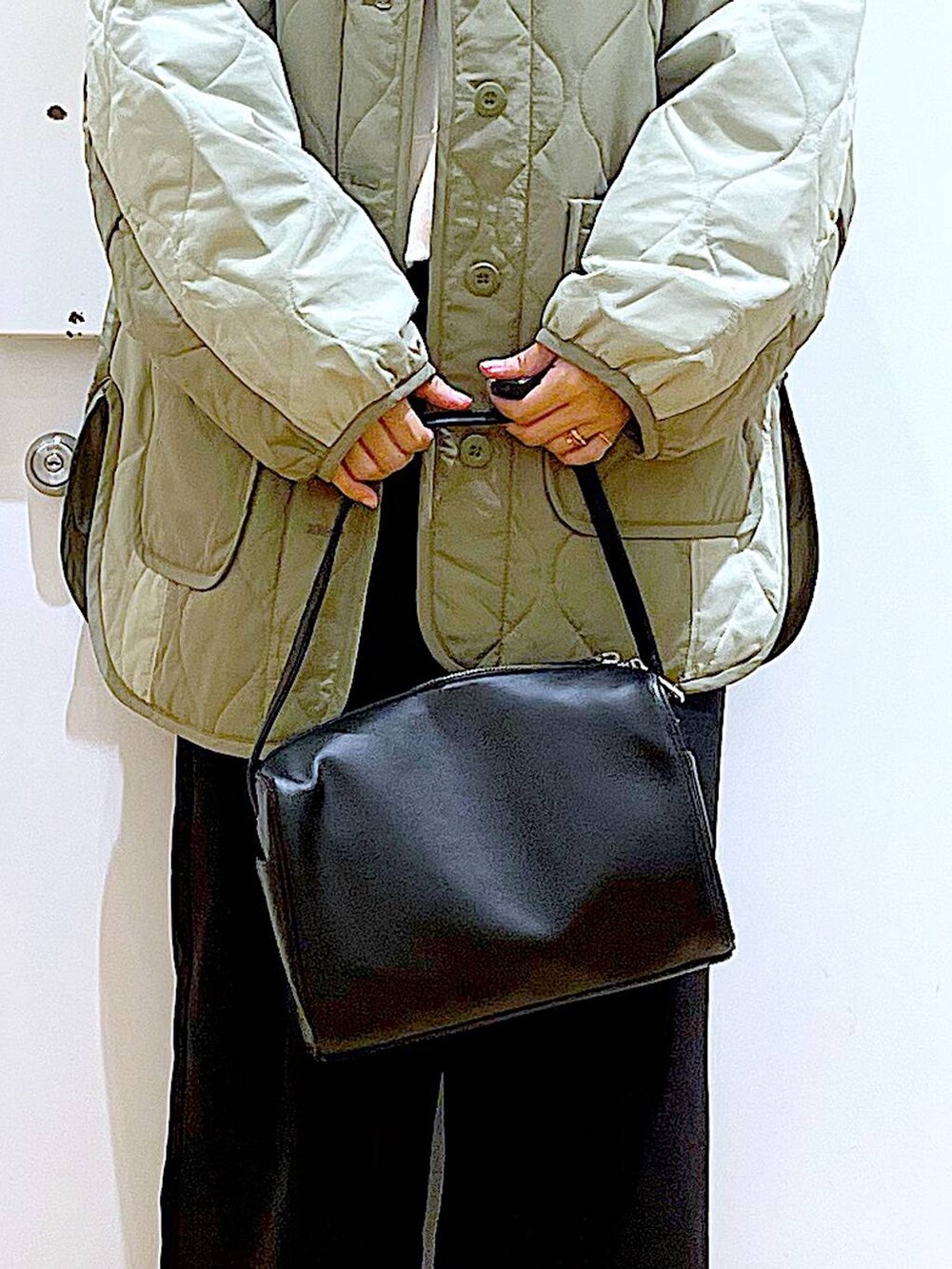 ブラック系のショルダーバッグ、ホワイト系のスウェット、ブラック系のブーツを着用したレディースの秋コーディネートの9枚目の写真