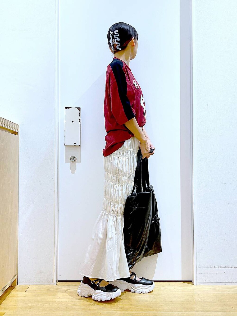 ホワイト系のスカート、ブラック系のスニーカー、ブラック系のトートバッグを着用したレディースの秋コーディネートの4枚目の写真