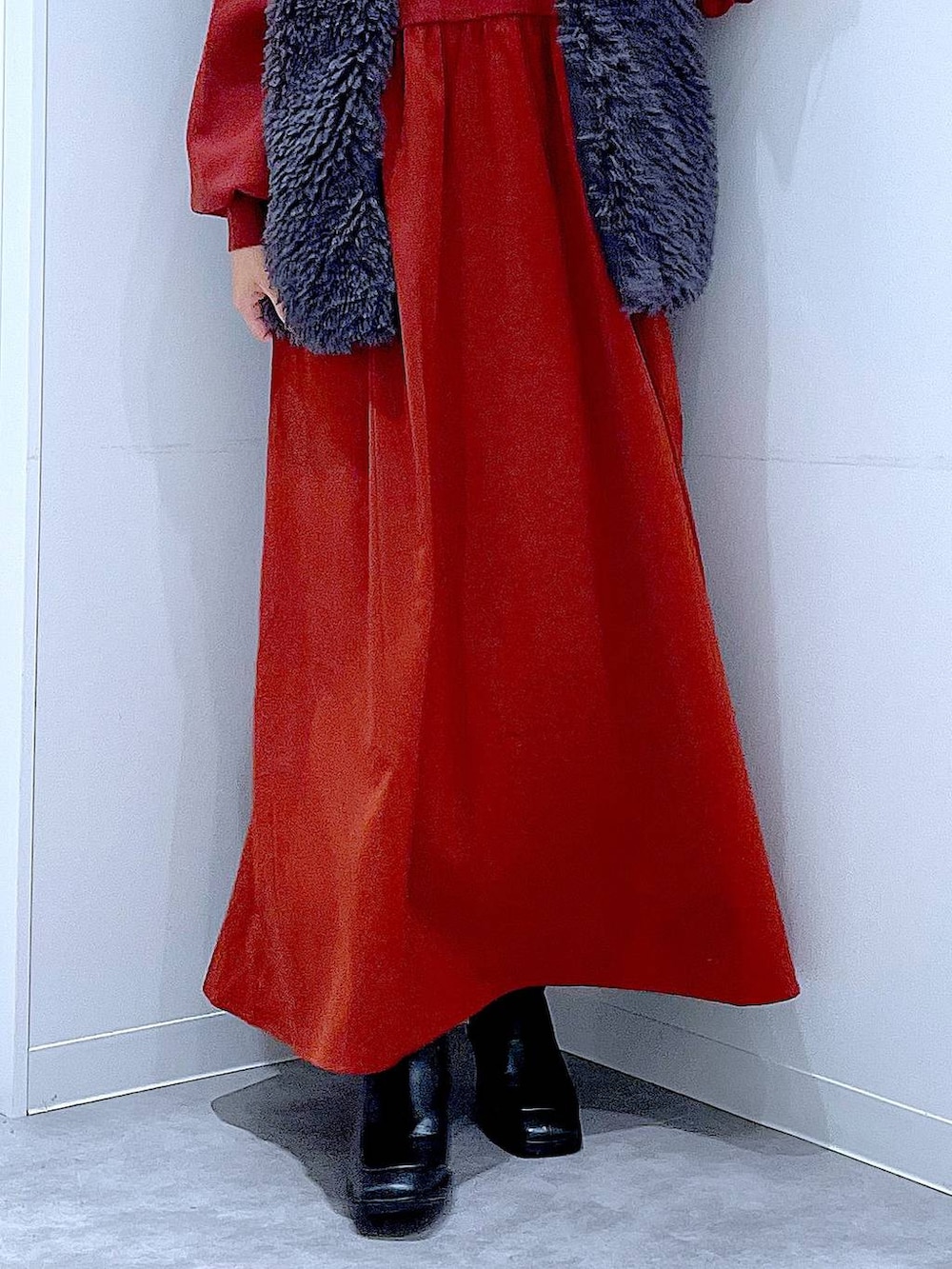 グレー系のベスト、ブラック系のブーツ、ホワイト系のショルダーバッグを着用したレディースの秋コーディネートの8枚目の写真