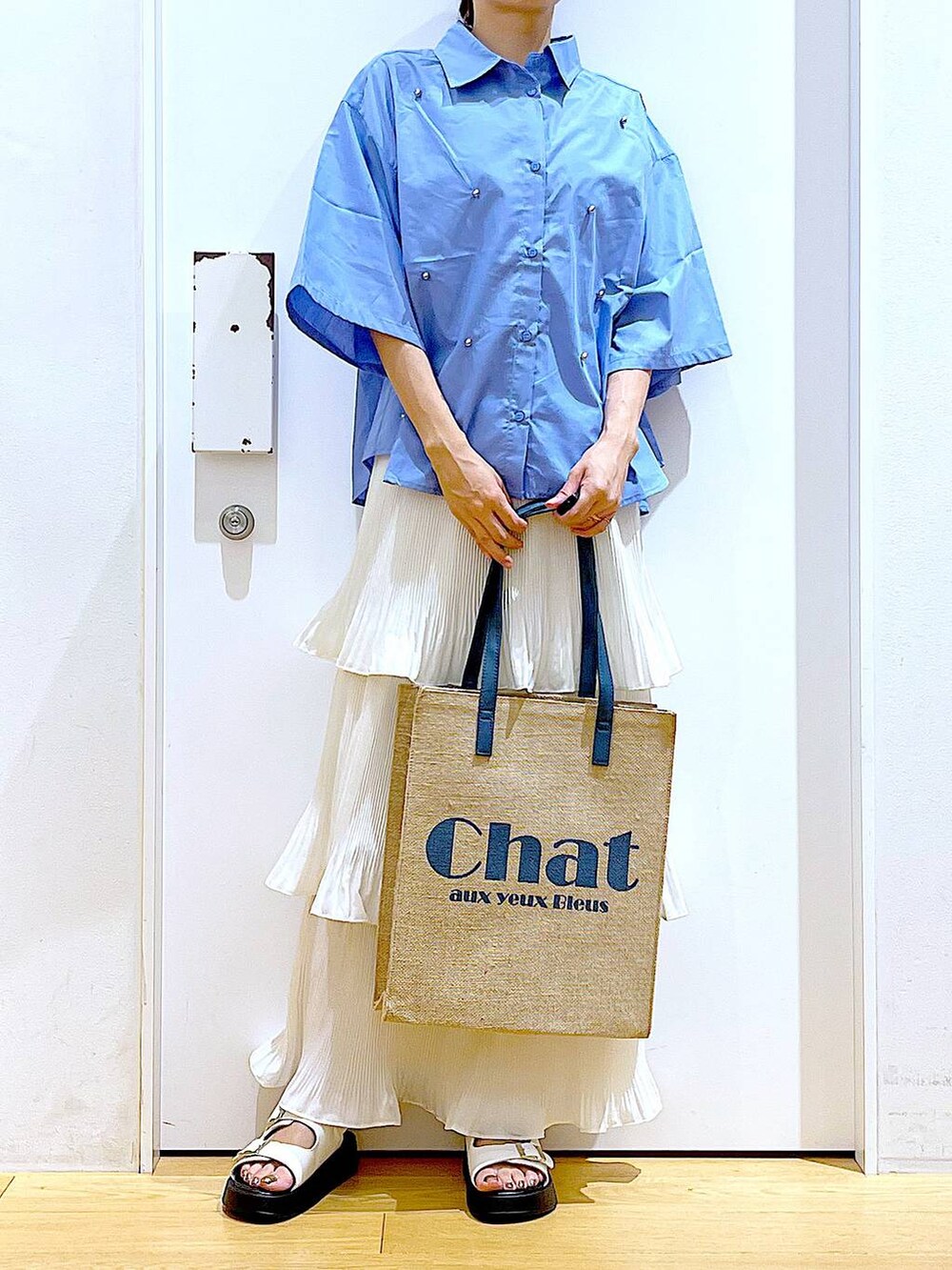 ベージュ系のスカート、ブルー系のトートバッグ、ホワイト系のサンダルを着用したレディースの夏コーディネートの6枚目の写真