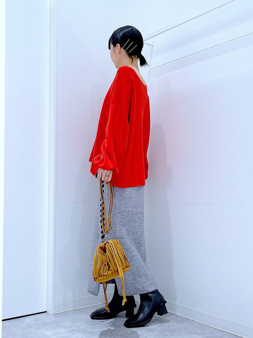 レッド系のニット/セーター、グレー系のスカート、ブラック系のブーツを着用したレディースの秋コーディネートの3枚目の写真