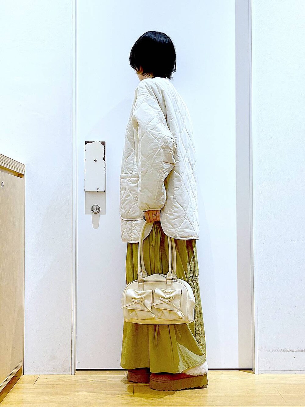 ベージュ系のブルゾン、ベージュ系のスリッポン、ホワイト系のハンドバッグを着用したレディースの秋コーディネートの3枚目の写真