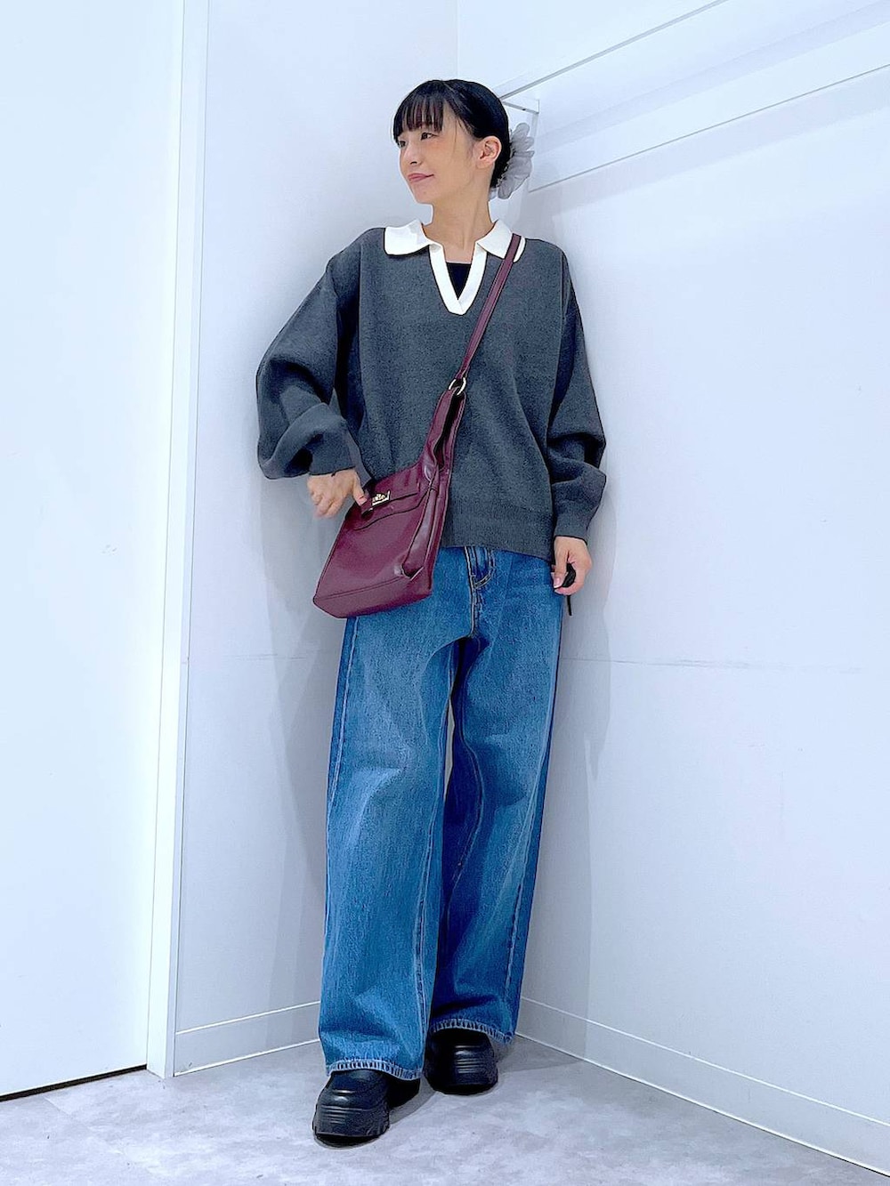 ブルー系のデニムパンツ、レッド系のショルダーバッグ、グレー系のニット/セーターを着用したレディースの秋コーディネートの2枚目の写真