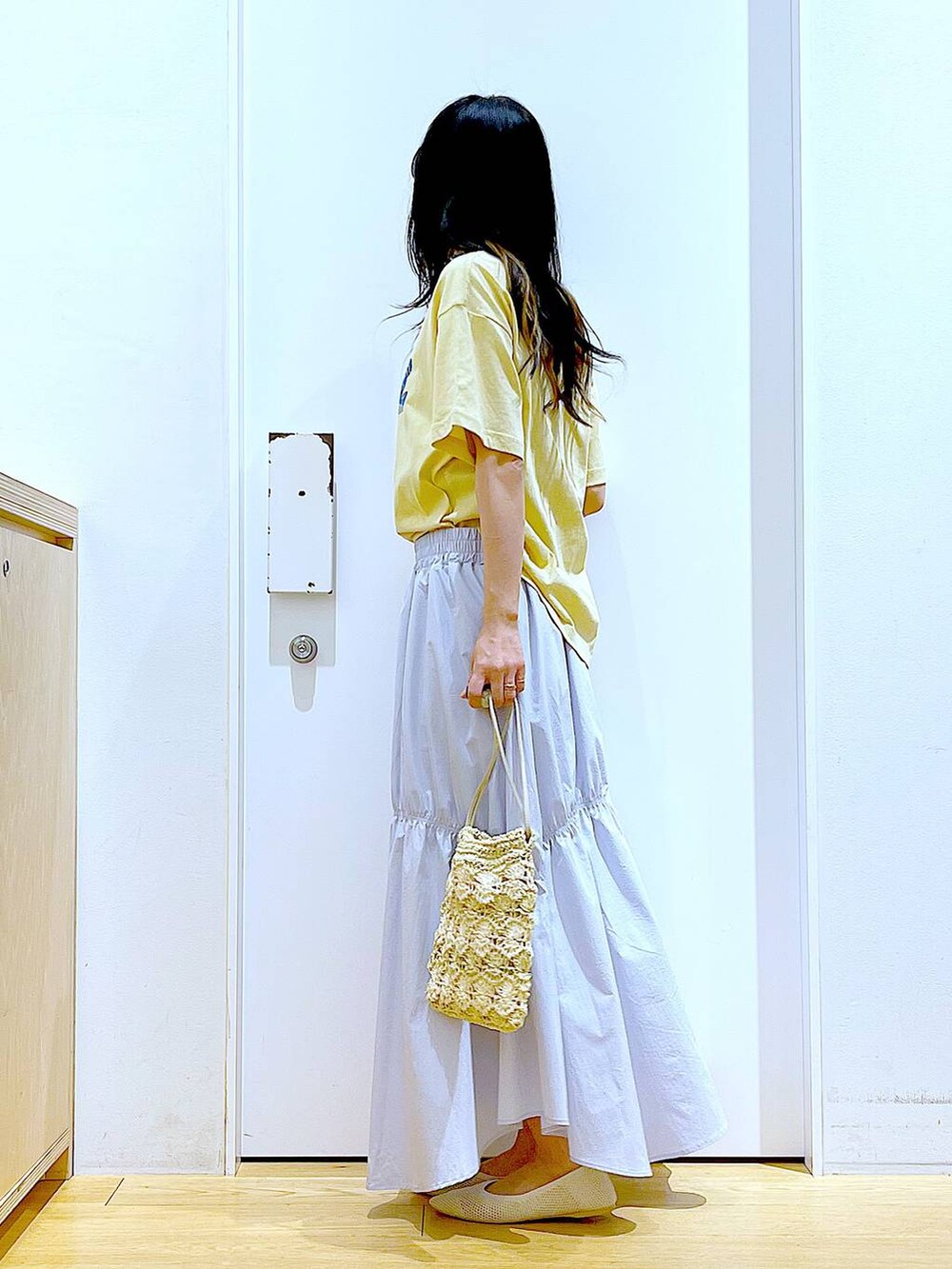 ブルー系のスカート、ホワイト系のパンプス、ベージュ系のショルダーバッグを着用したレディースの春コーディネートの3枚目の写真