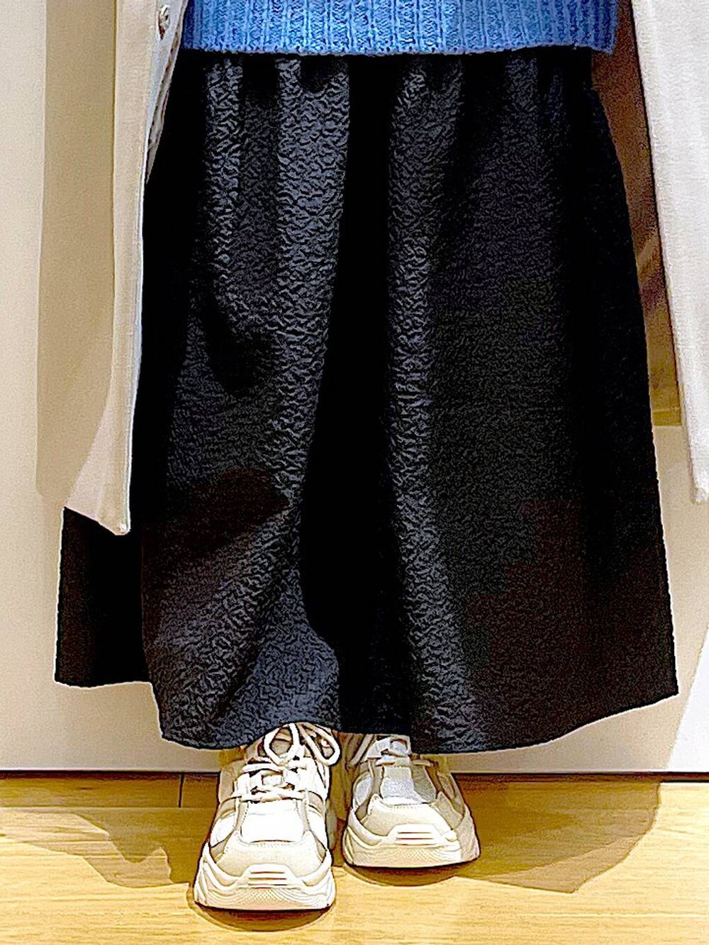 シルバー系のショルダーバッグ、ベージュ系のスニーカー、ベージュ系のノーカラーコートを着用したレディースの冬コーディネートの8枚目の写真