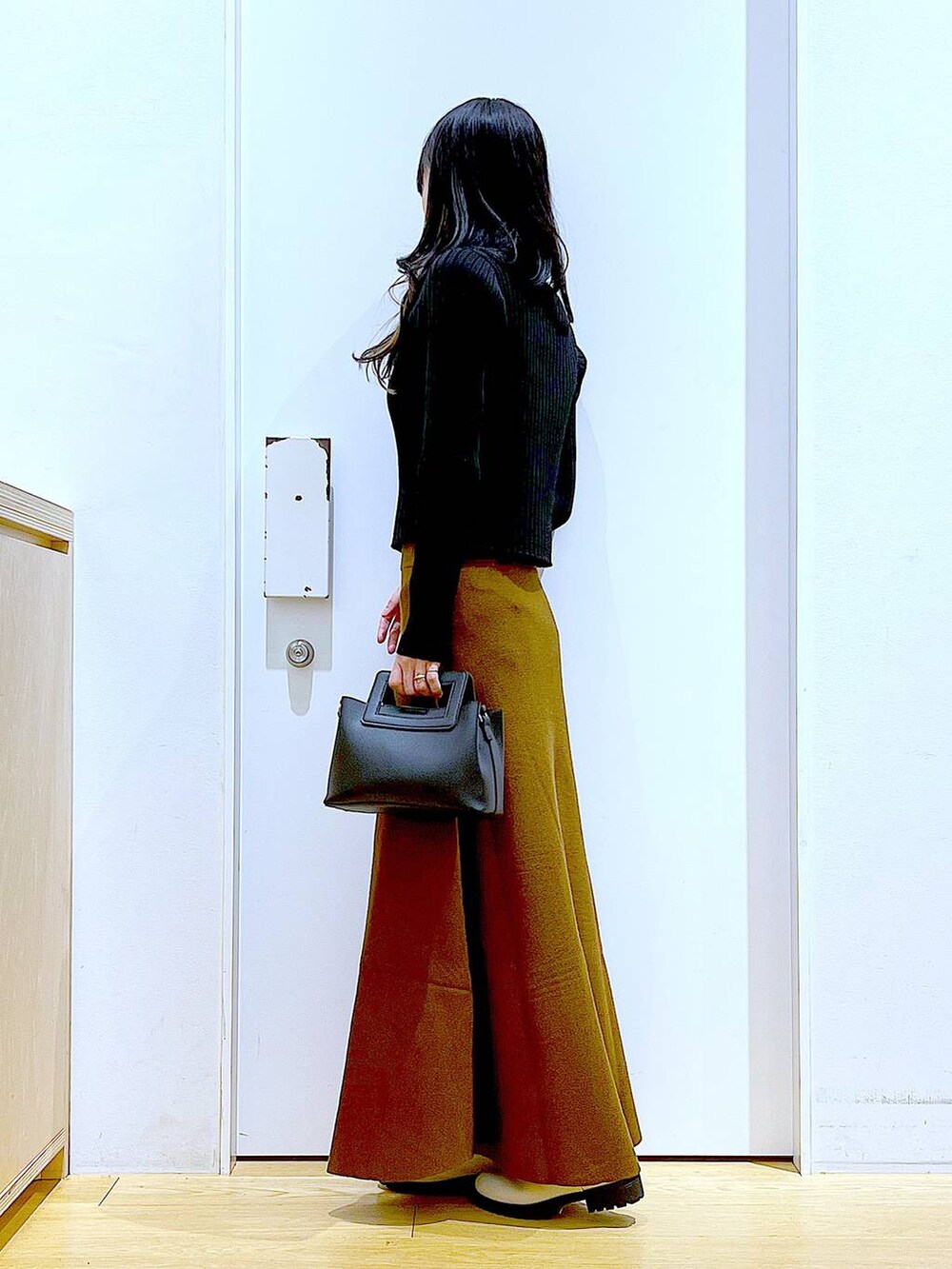 ブラック系のカーディガン/ボレロ、ブラウン系のスカート、ベージュ系のブーツを着用したレディースの冬コーディネートの3枚目の写真