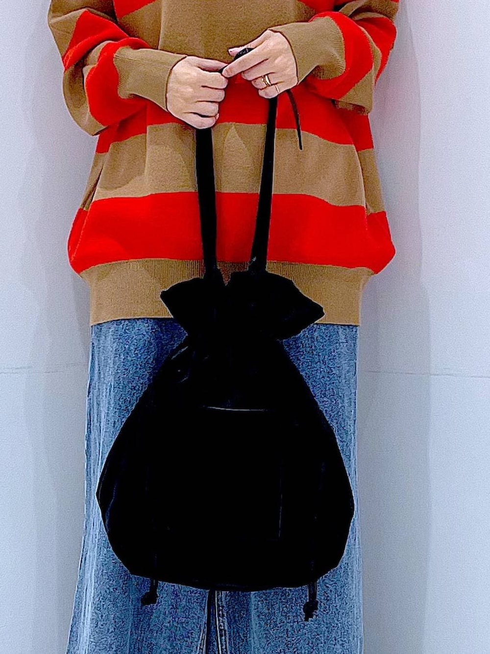 ブラック系のトートバッグ、レッド系のニット/セーター、ブルー系のデニムパンツを着用したレディースの冬コーディネートの9枚目の写真