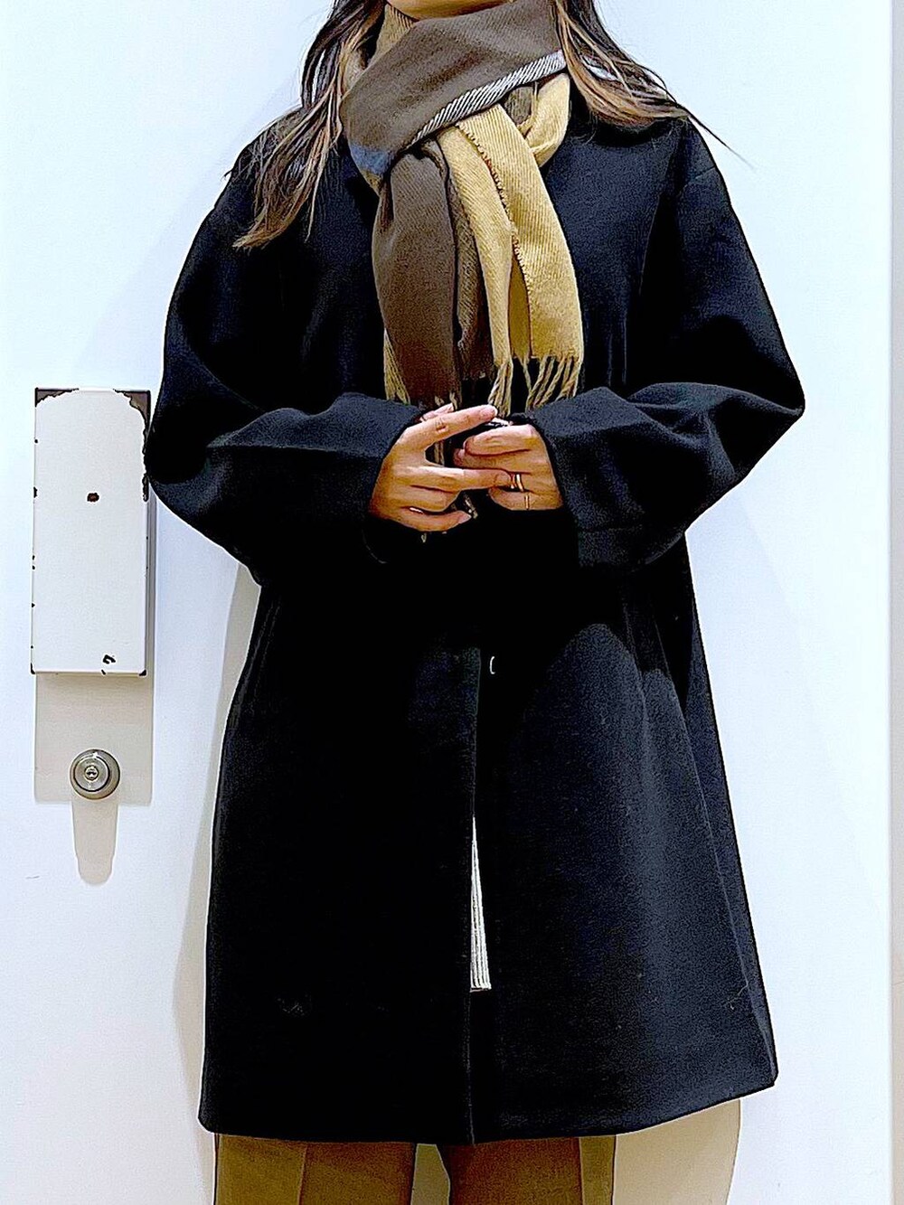 ブラック系のノーカラーコート、グレー系のショルダーバッグ、グレー系のニット/セーターを着用したレディースの冬コーディネートの5枚目の写真