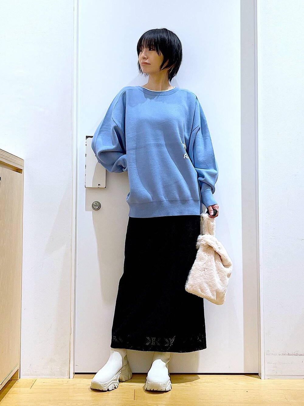 ブルー系のニット/セーター、ホワイト系のショルダーバッグ、ベージュ系のブーツを着用したレディースの冬コーディネートの2枚目の写真