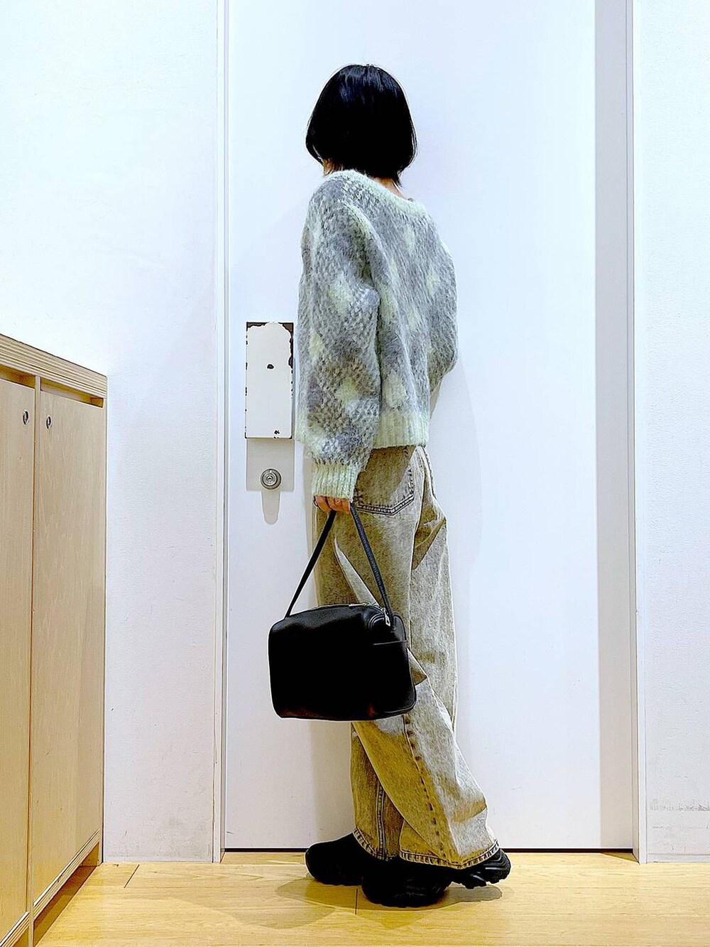 ブラック系のショルダーバッグ、ブラック系のブーツ、ベージュ系のデニムパンツを着用したレディースの冬コーディネートの3枚目の写真