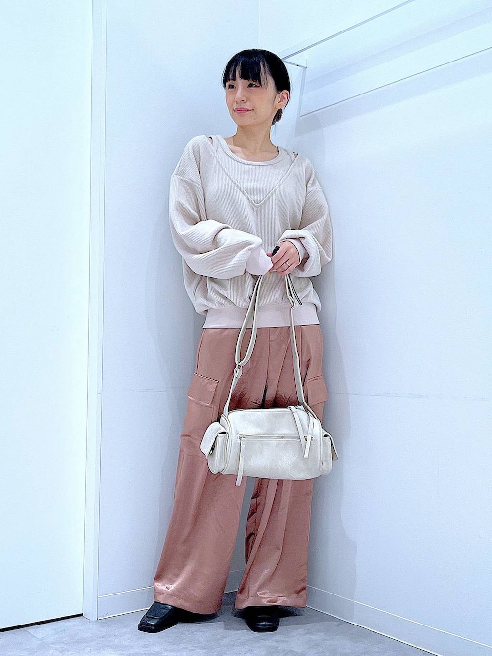 ブラック系のブーツ、ベージュ系のニット/セーター、ピンク系のカーゴパンツを着用したレディースの冬コーディネートの2枚目の写真