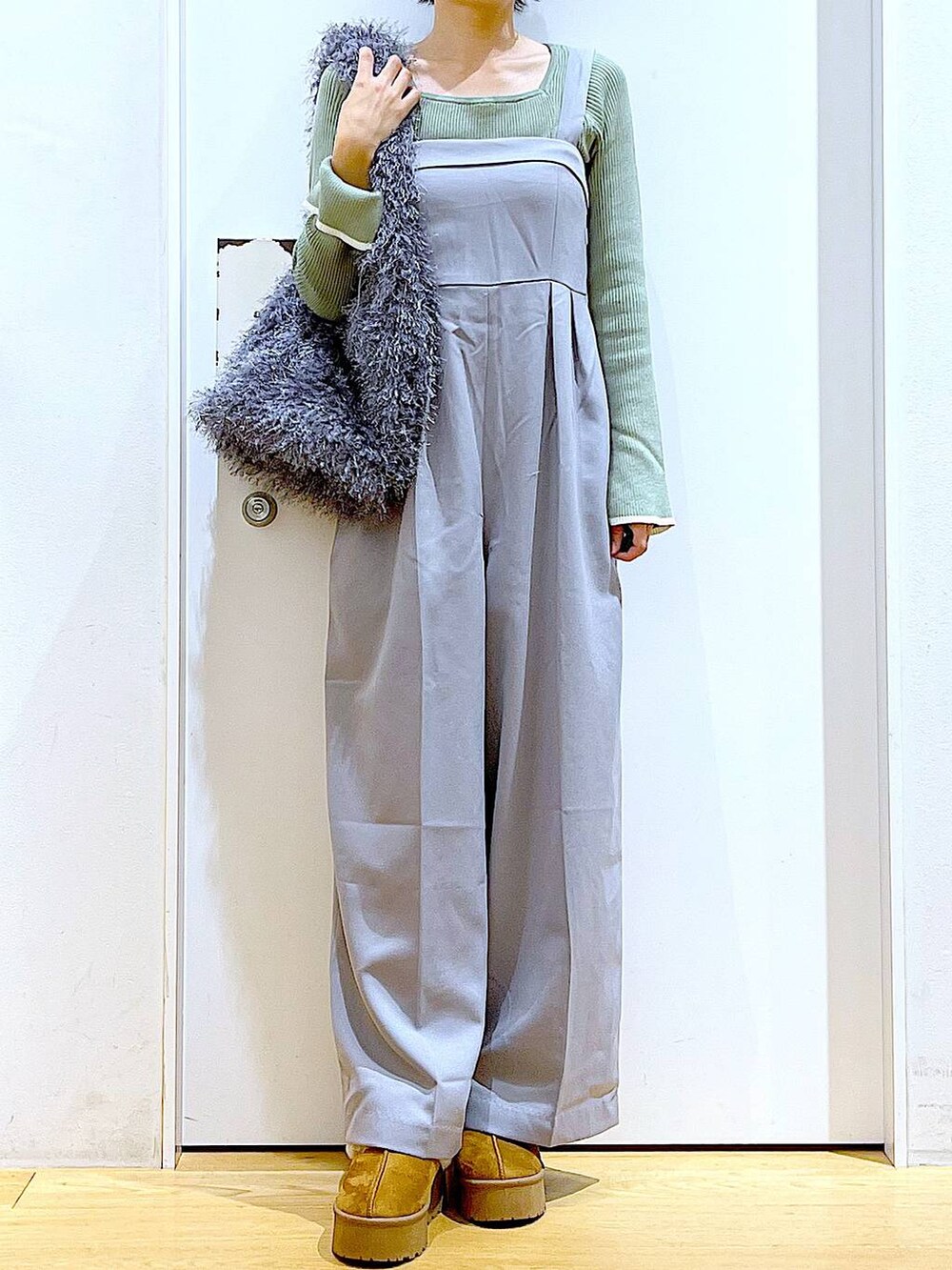 グリーン系のニット/セーター、グレー系のサロペット/オーバーオール、グレー系のショルダーバッグを着用したレディースの秋コーディネートの6枚目の写真