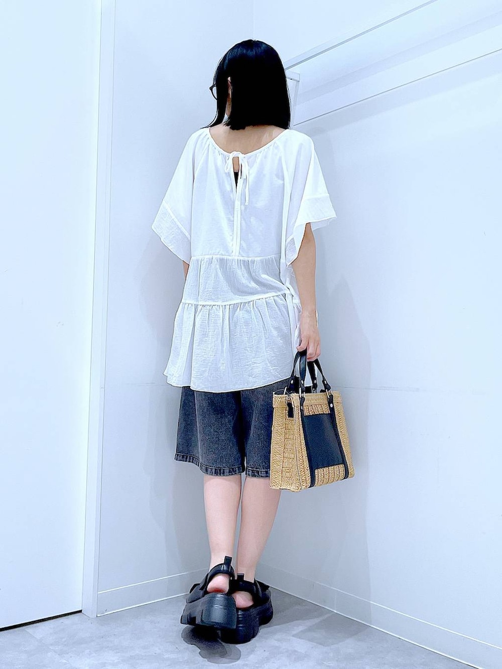 ベージュ系のショルダーバッグ、ブラック系のサンダル、ホワイト系のTシャツ/カットソーを着用したレディースの夏コーディネートの5枚目の写真