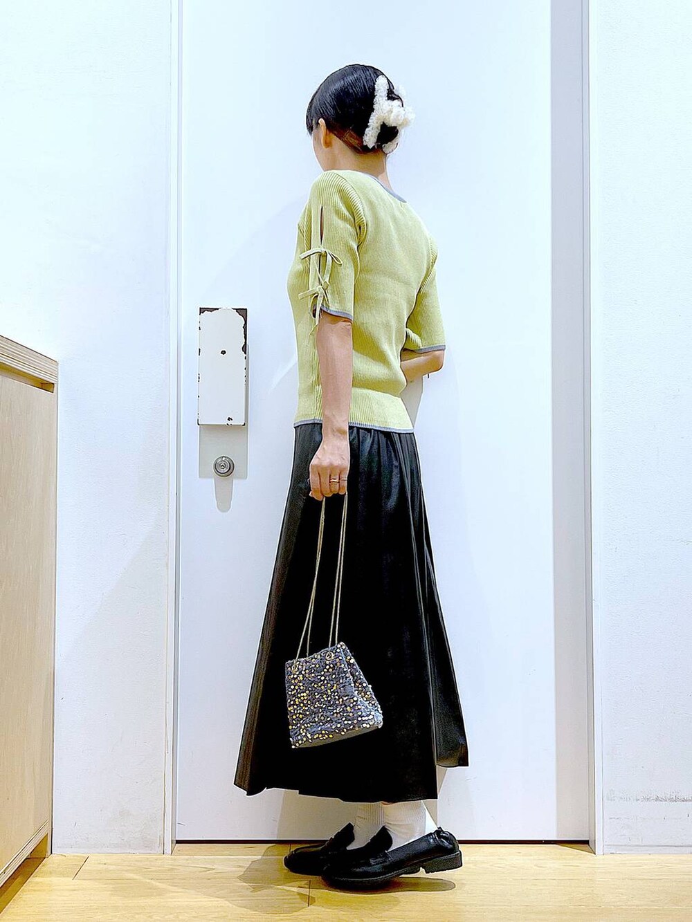 グレー系のショルダーバッグ、ブラック系のローファー、イエロー系のニット/セーターを着用したレディースの秋コーディネートの3枚目の写真