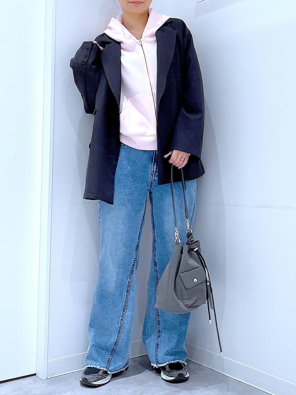 グレー系のテーラードジャケット、ブルー系のデニムパンツ、ピンク系のパーカーを着用したレディースの春コーディネートの6枚目の写真