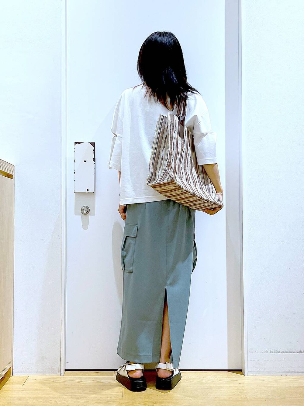 ホワイト系のサンダル、グリーン系のスカート、ブラウン系のトートバッグを着用したレディースの夏コーディネートの5枚目の写真