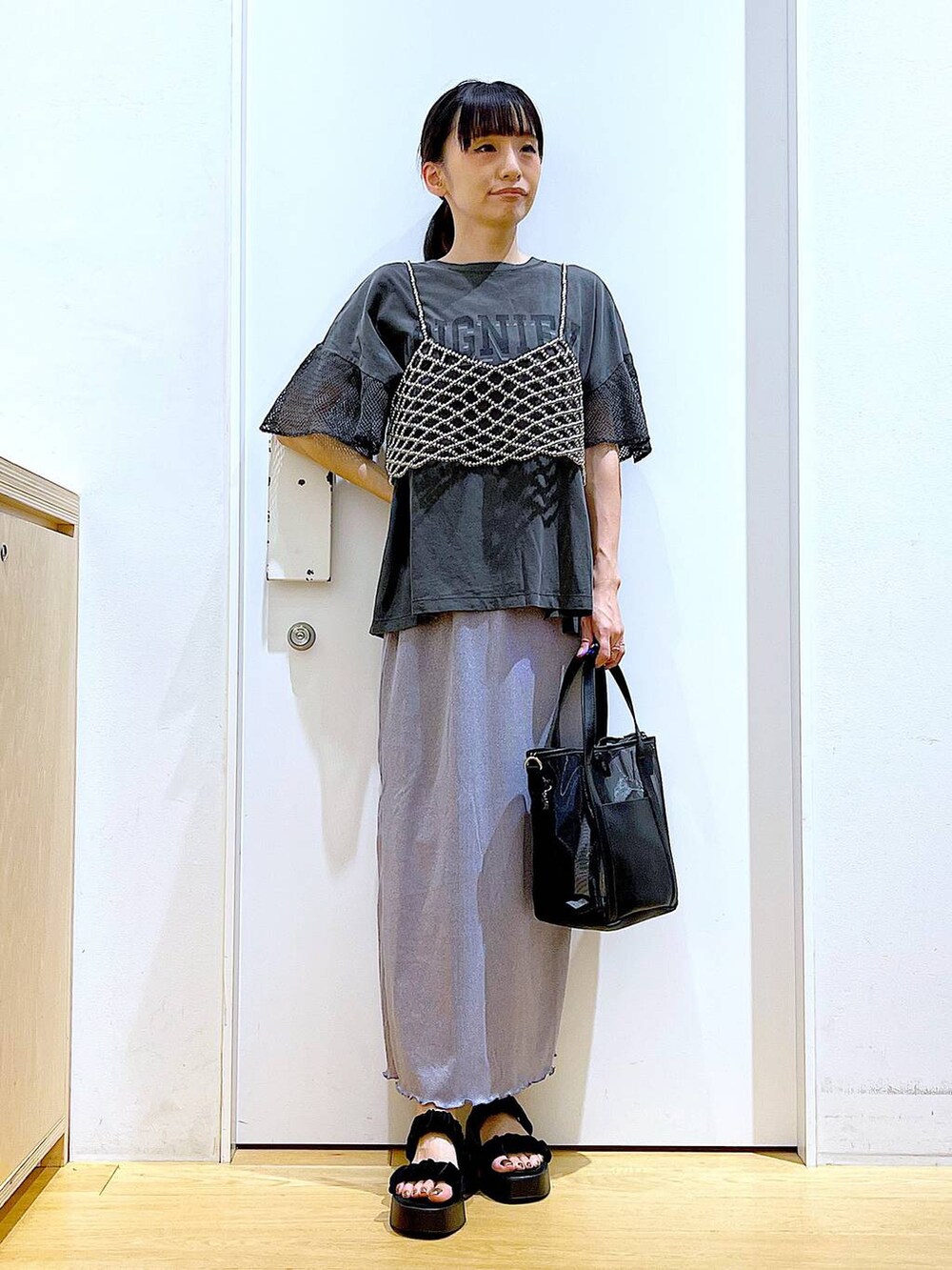 パープル系のスカート、ブラック系のサンダル、ブラック系のトートバッグを着用したレディースの夏コーディネートの2枚目の写真