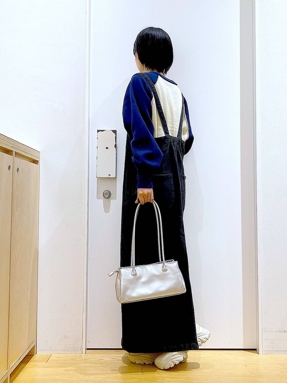 グレー系のジャンパースカート、シルバー系のトートバッグ、ベージュ系のブーツを着用したレディースの冬コーディネートの3枚目の写真