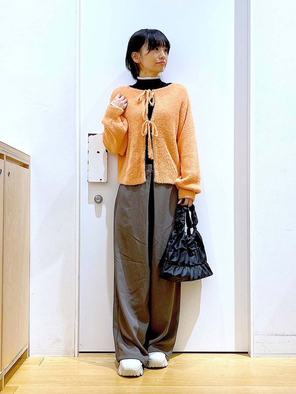 ブラック系のニット/セーター、ベージュ系のブーツ、ブラック系のショルダーバッグを着用したレディースの冬コーディネートの2枚目の写真