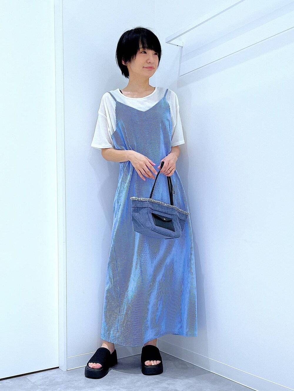 ブルー系のショルダーバッグ、ブラック系のサンダル、ホワイト系のTシャツ/カットソーを着用したレディースの夏コーディネートの2枚目の写真