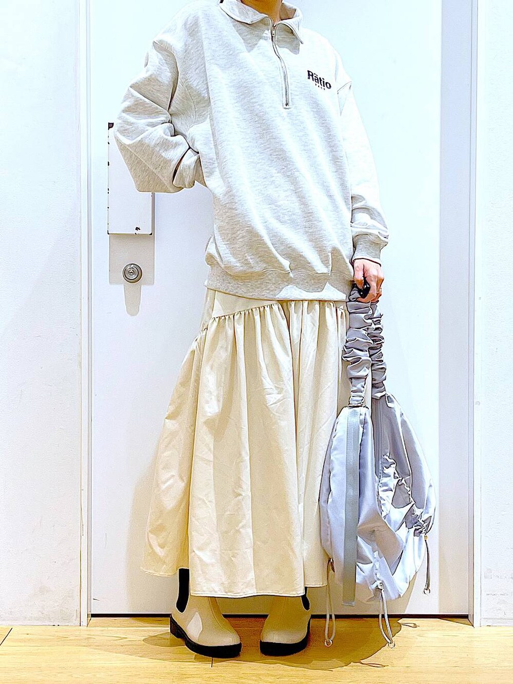 ベージュ系のスウェット、ホワイト系のスカート、ベージュ系のブーツを着用したレディースの春コーディネートの6枚目の写真