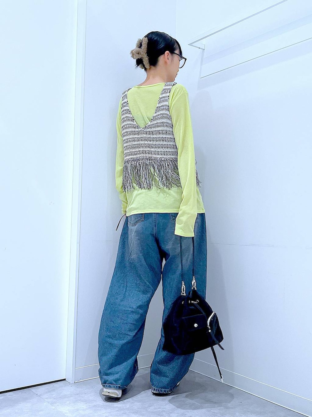 ブルー系のデニムパンツ、グリーン系のTシャツ/カットソー、ブラック系のショルダーバッグを着用したレディースの春コーディネートの5枚目の写真