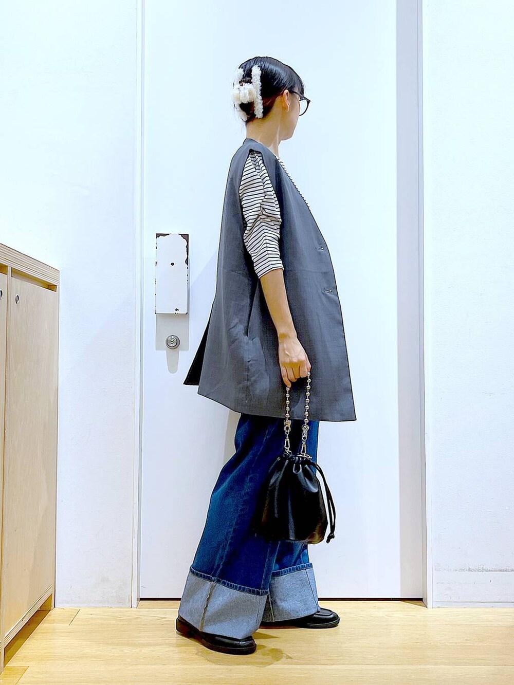 ブラック系のショルダーバッグ、ブラック系のローファー、グレー系のベストを着用したレディースの秋コーディネートの4枚目の写真