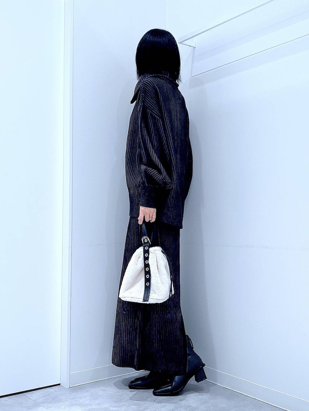 ホワイト系のハンドバッグ、ブラック系のスカート、ブラック系のニット/セーターを着用したレディースの秋コーディネートの3枚目の写真