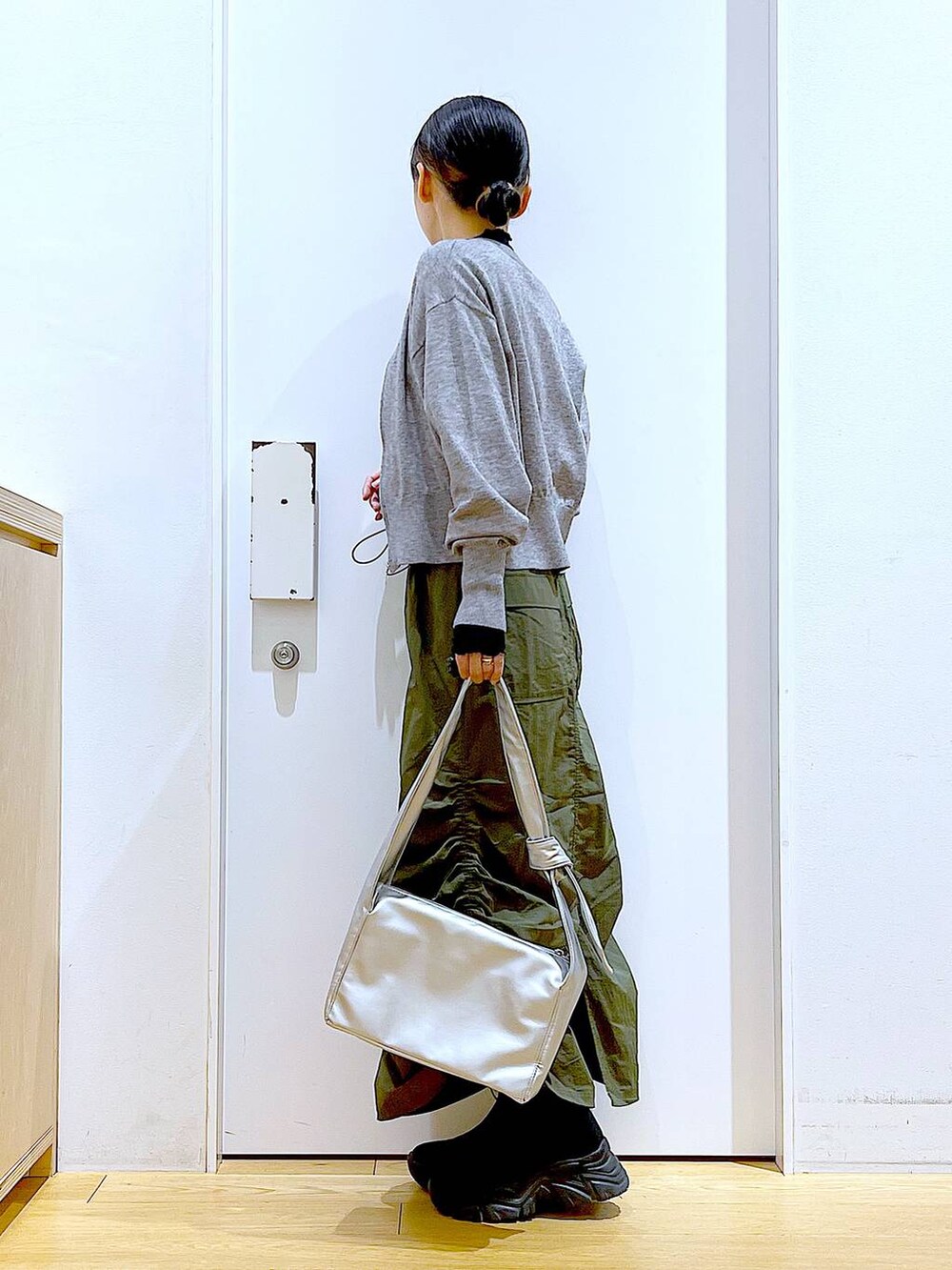 ブラック系のTシャツ/カットソー、グレー系のカーディガン/ボレロ、ブラック系のブーツを着用したレディースの冬コーディネートの3枚目の写真