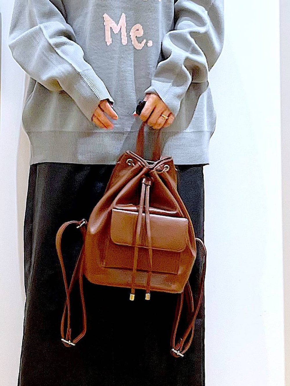 グレー系のニット/セーター、ブラウン系のバックパック/リュック、ブラック系のスカートを着用したレディースの冬コーディネートの9枚目の写真